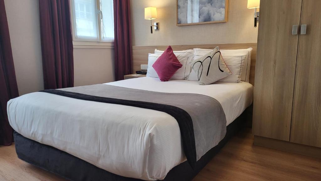 a hotel room with a large white bed with pillows at Magda Champs Elysées in Paris