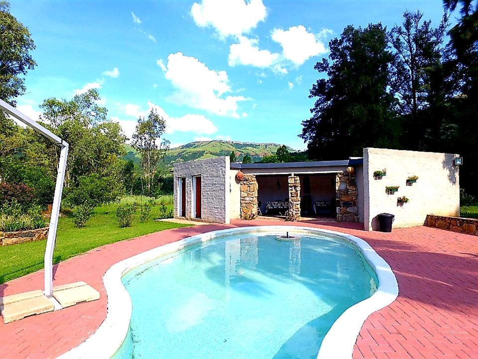 a swimming pool in front of a house at Wayside Lodge in Waterval Boven