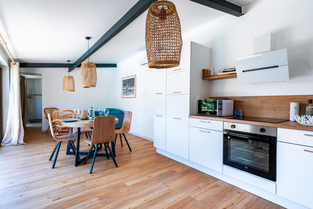 uma cozinha com armários brancos e uma mesa com cadeiras em La Piscine em Suze-la-Rousse