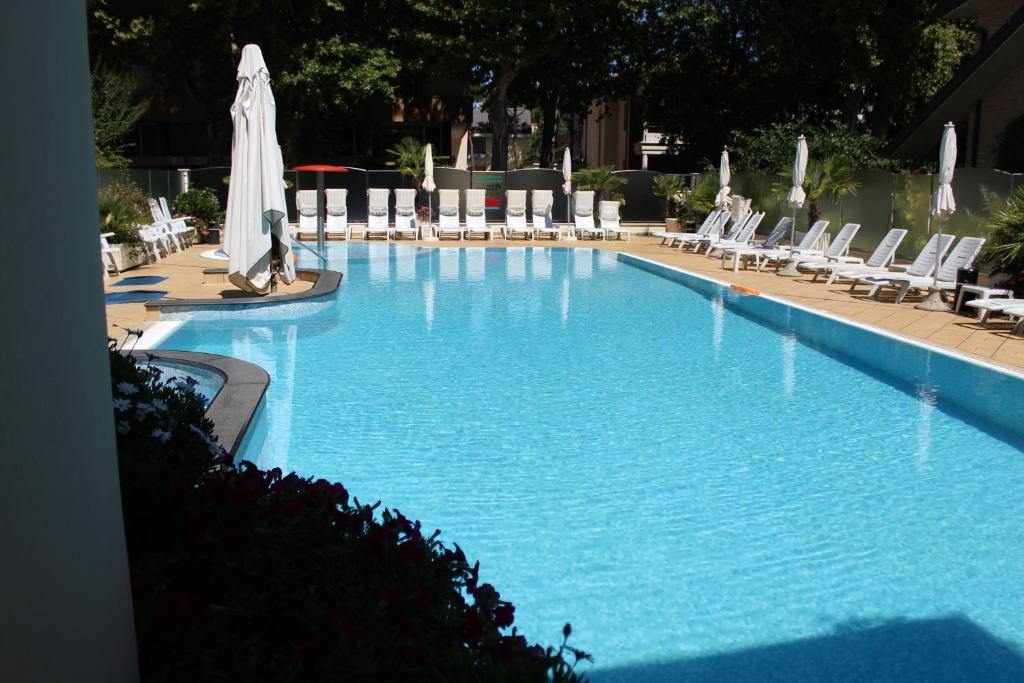 uma grande piscina com cadeiras e um guarda-sol em Hotel Rosenblatt em Cervia