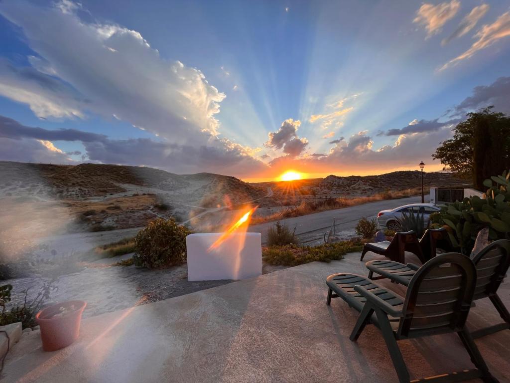 einen Blick auf den Sonnenuntergang von einer Terrasse mit 2 Stühlen in der Unterkunft Cave Holidays Andalucia in Los Carriones