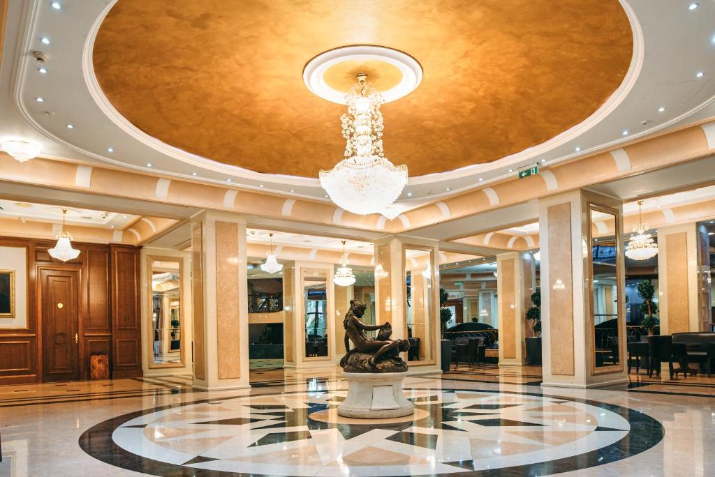 a lobby with a chandelier and a statue at A Hoteli - Hotel Izvor in Arandelovac