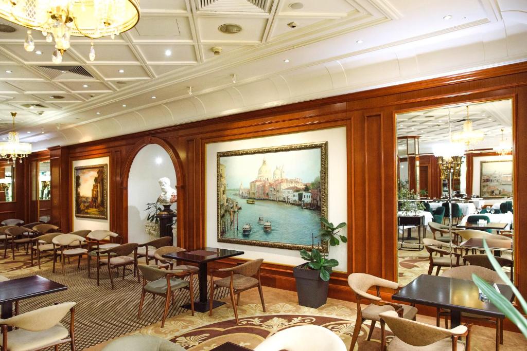 a restaurant with tables and chairs and a painting on the wall at A Hoteli - Hotel Izvor in Arandelovac