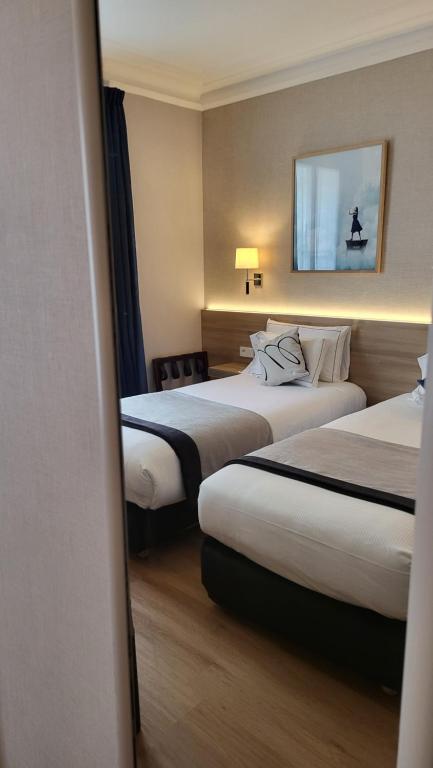 a hotel room with two beds and a mirror at Magda Champs Elysées in Paris