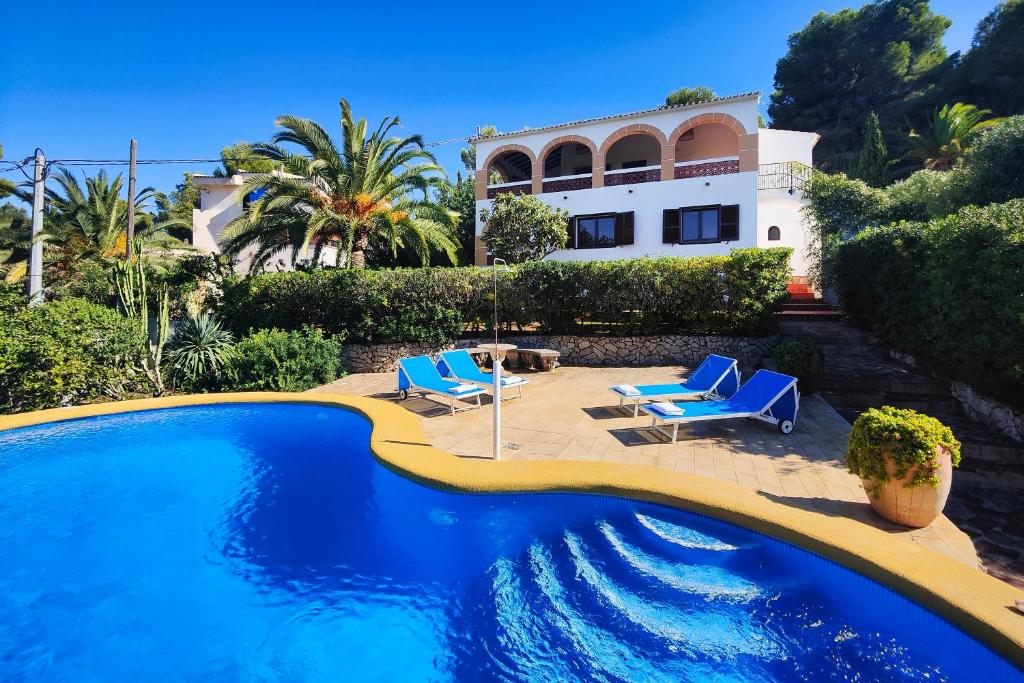 una casa con piscina y 2 sillas azules en Villa Marta, en Denia