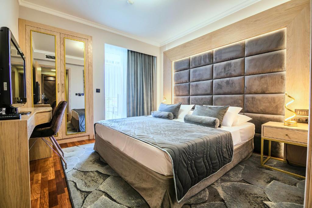 a bedroom with a large bed and a television at A Hoteli - Hotel Izvor in Arandelovac