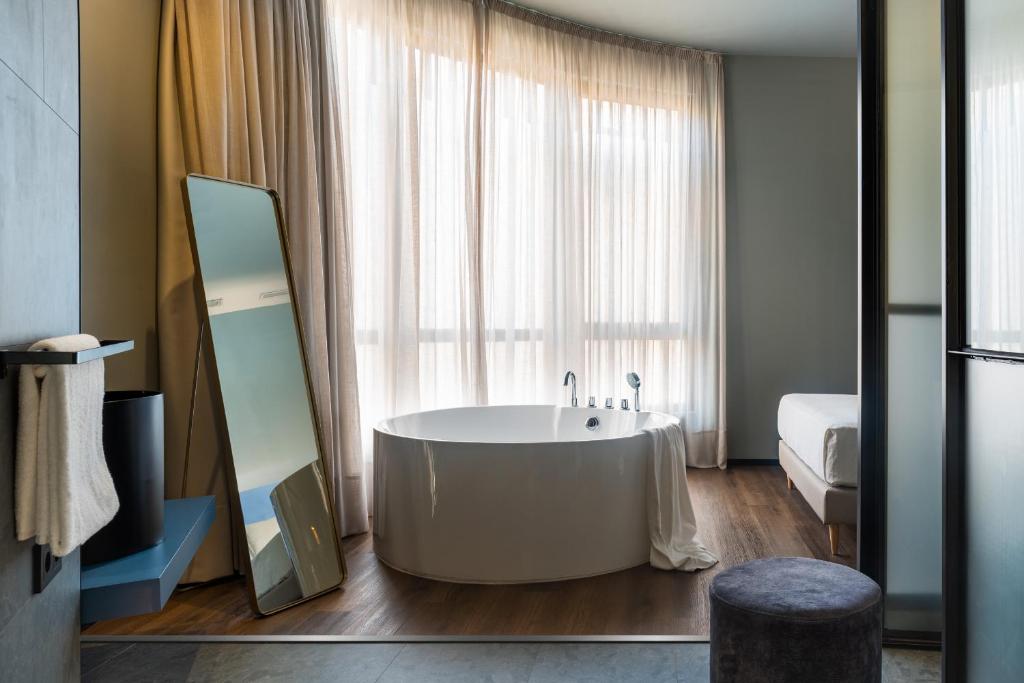 a bathroom with a tub in front of a window at Muralla Sevilla Suites By Lola in Seville