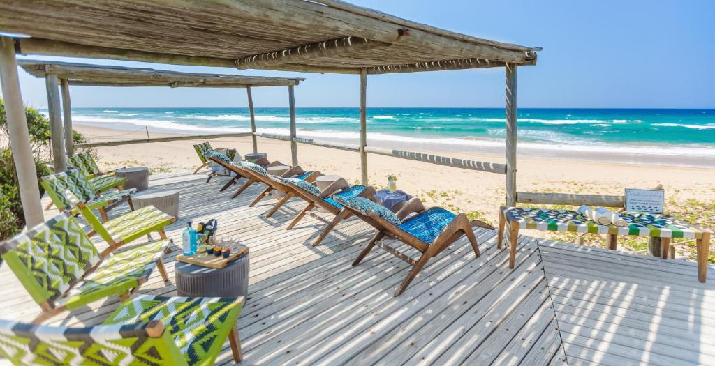a wooden deck with chairs and the beach at Thonga Beach Lodge in Mabibi