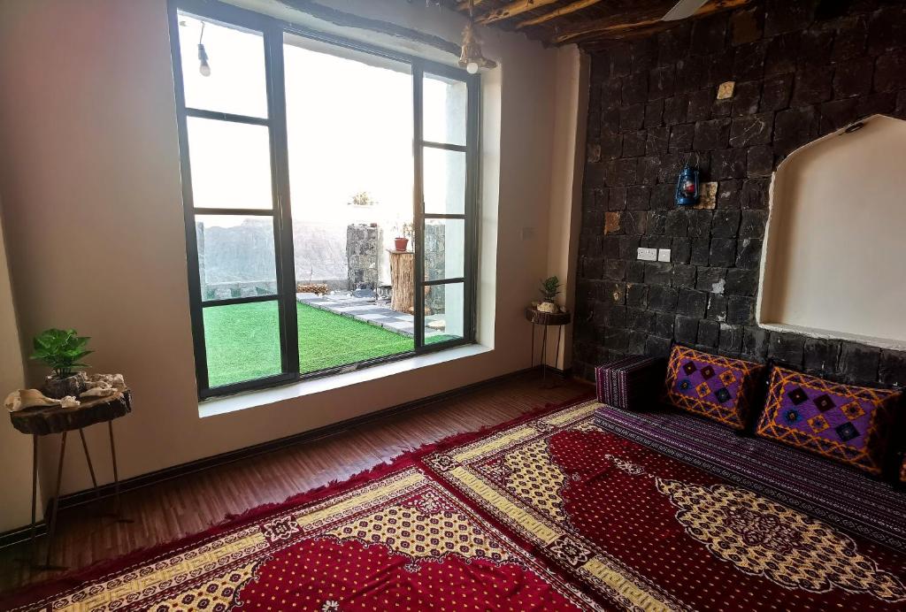ROSES HOUSE OMAN 2 في Al ‘Aqar: غرفة معيشة مع أريكة ونافذة كبيرة
