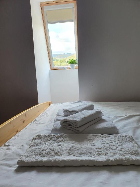 a bed with three towels on it with a window at Magic Rooms in Gura Teghii