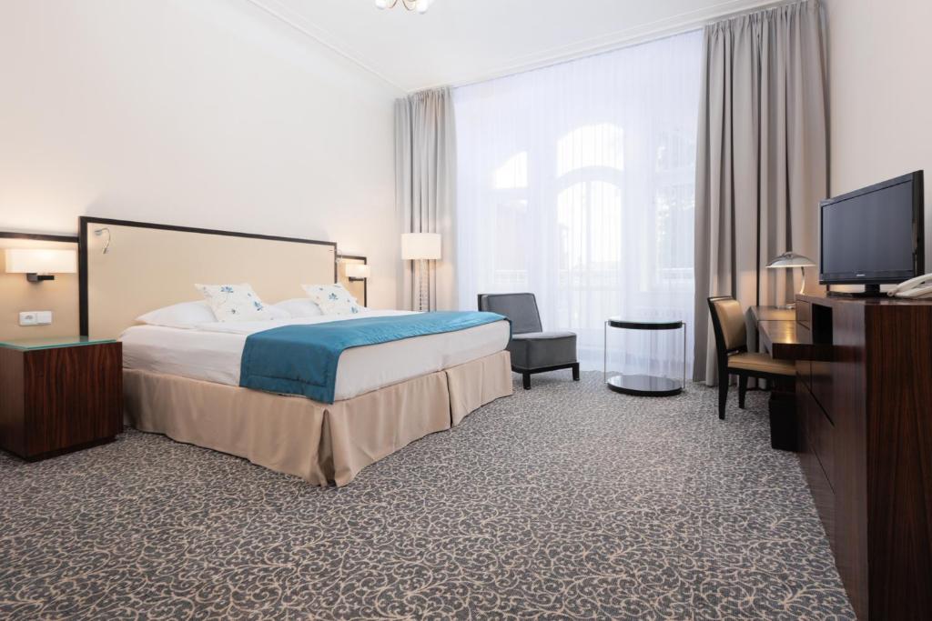 a hotel room with a bed and a flat screen tv at OREA Spa Hotel Bohemia Mariánské Lázně in Mariánské Lázně