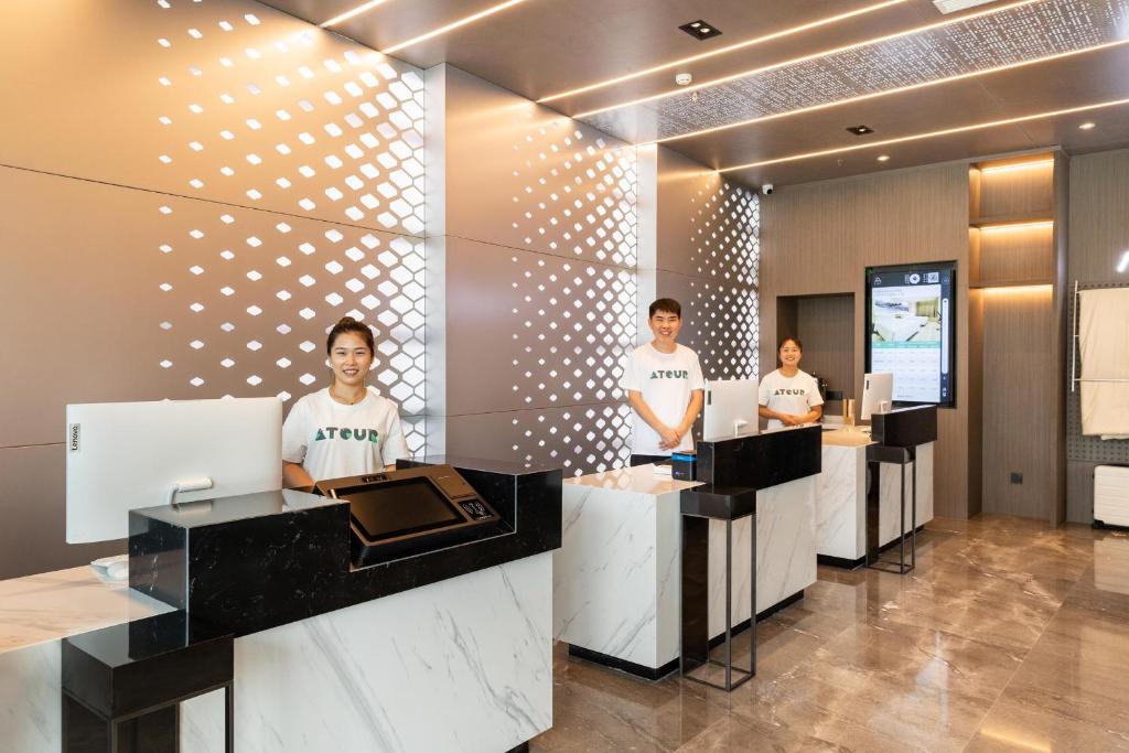 4 Personen stehen an einer Theke in einer Hotellobby in der Unterkunft Atour Hotel Hefei Feidong High Speed Railway Station in Feidong