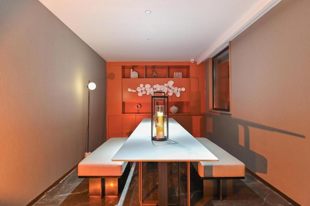LuliangにあるAtour Hotel Luliang Central Parkのオレンジ色の壁のダイニングルーム(テーブル、ベンチ2台付)
