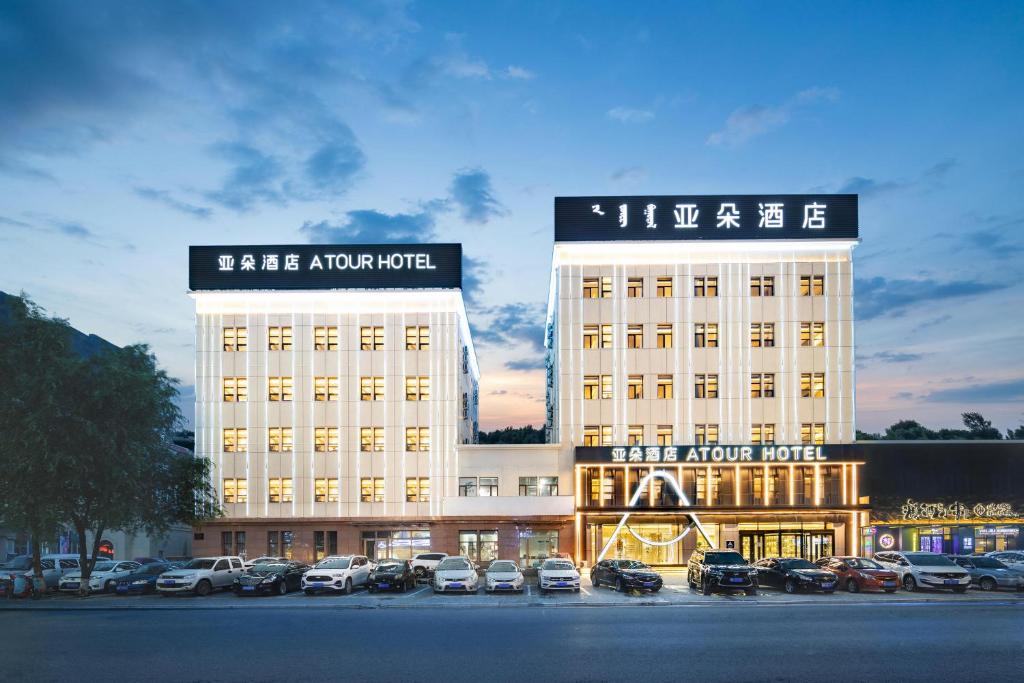 un gran edificio con coches estacionados en un estacionamiento en Atour Hotel Tongliao Wanda Plaza, en Tongliao