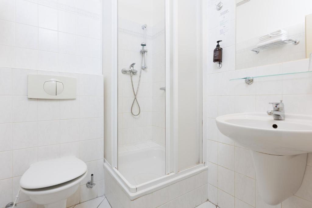 a white bathroom with a toilet and a sink at OREA Spa Hotel Bohemia Mariánské Lázně in Mariánské Lázně