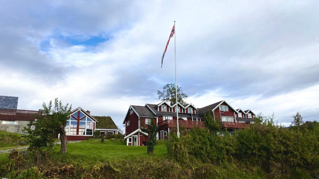 a house with a flag flying in front of it at Bjørnafjorden Hotell in Osøyro