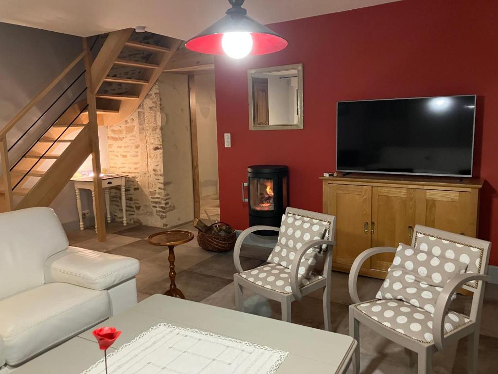een woonkamer met een tv en een bank en stoelen bij LA VELOGIROUETTE in Feuguerolles-sur-Orne