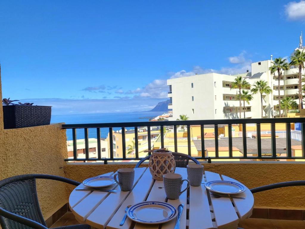 a table on a balcony with a view of the ocean at Sunset Arena Beach by HelloApartments in Puerto de Santiago