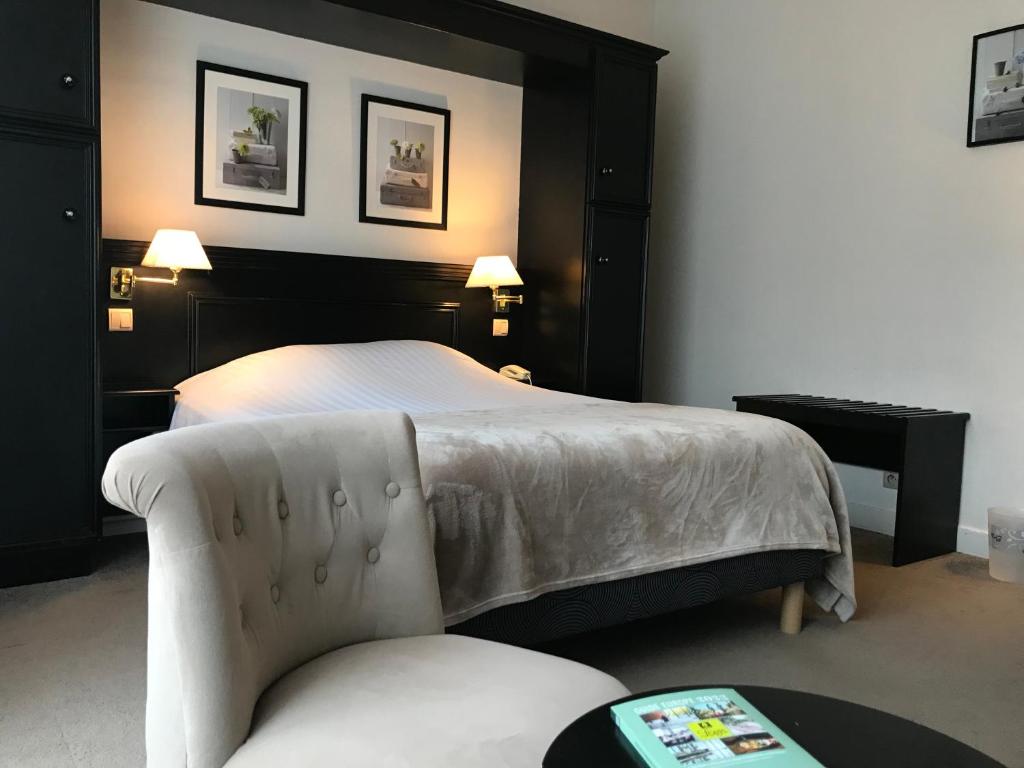 une chambre d'hôtel avec un lit et une chaise dans l'établissement Logis Hôtel-Restaurant Les Airelles, à Neufchâtel-en-Bray