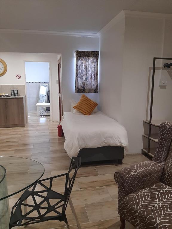 um quarto com uma cama, uma mesa e uma cadeira em Sleep@161 Benade Drive em Bloemfontein