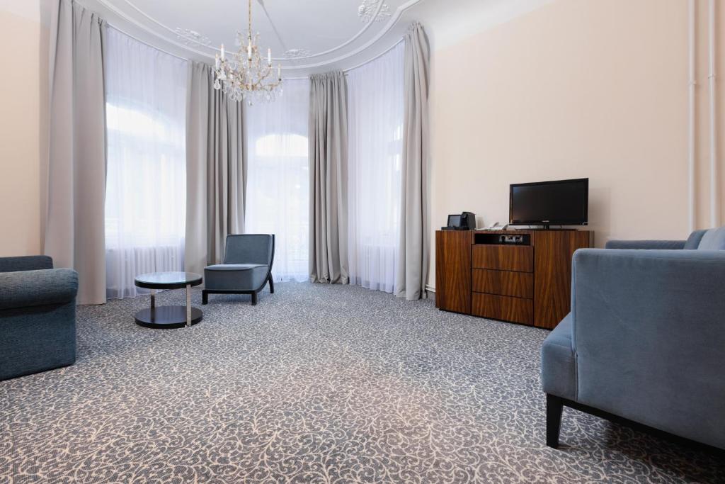 a living room with chairs and a tv and a couch at OREA Spa Hotel Bohemia Mariánské Lázně in Mariánské Lázně