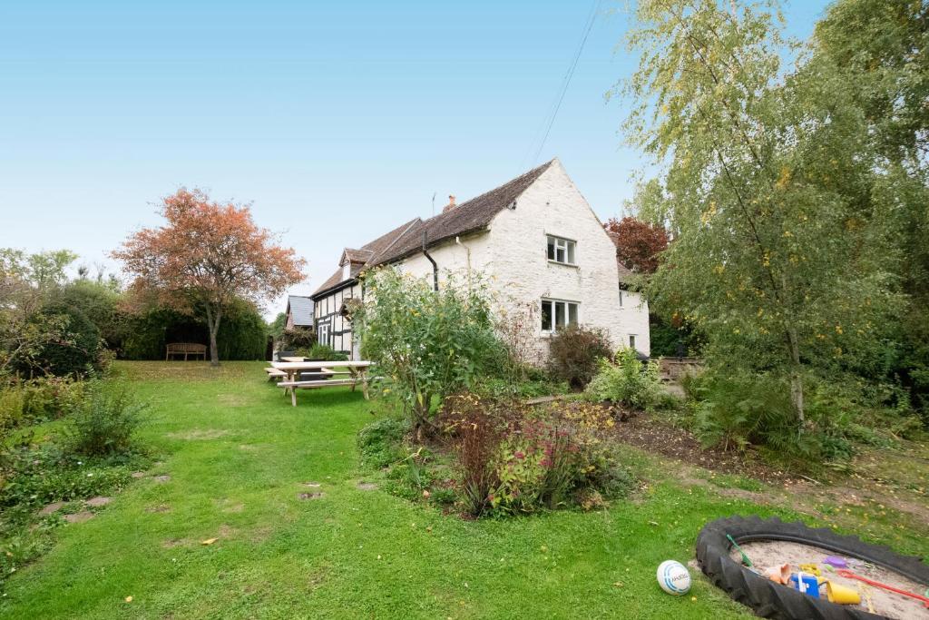 an old white house with a picnic table in the yard at Little Cowarne Court in Little Cowarne