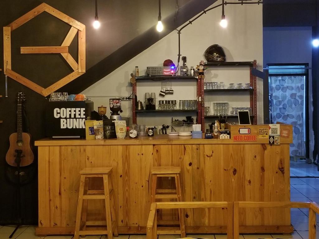 a wooden bar with two stools and a guitar at CoffeeBunk Hostel in Tangerang