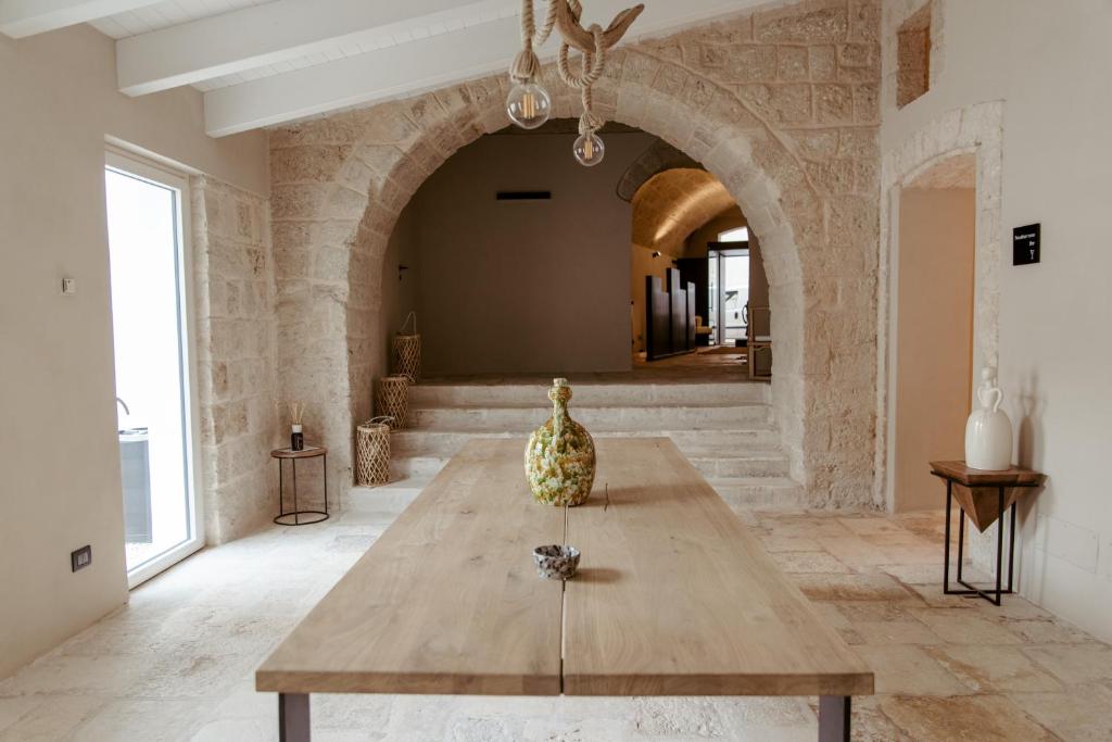 Cette grande chambre dispose d'une table en bois et d'une voûte. dans l'établissement Le Carasse Boutique Hotel, à Mola di Bari