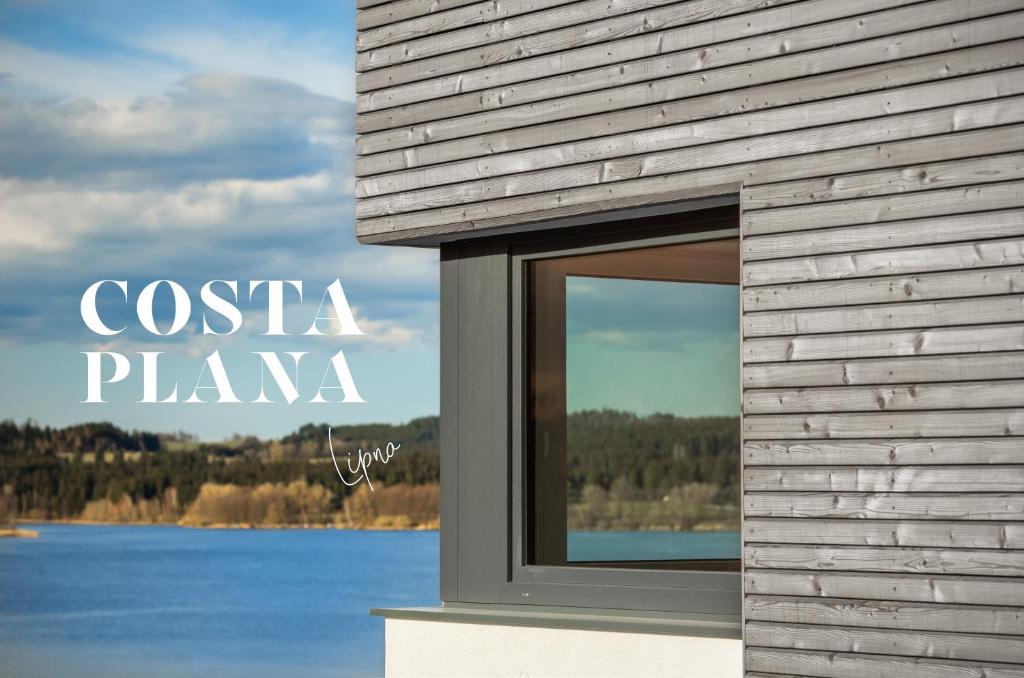 a window on a building with a view of a lake at Apartmány Panelka Costa Plana Lipno in Černá v Pošumaví