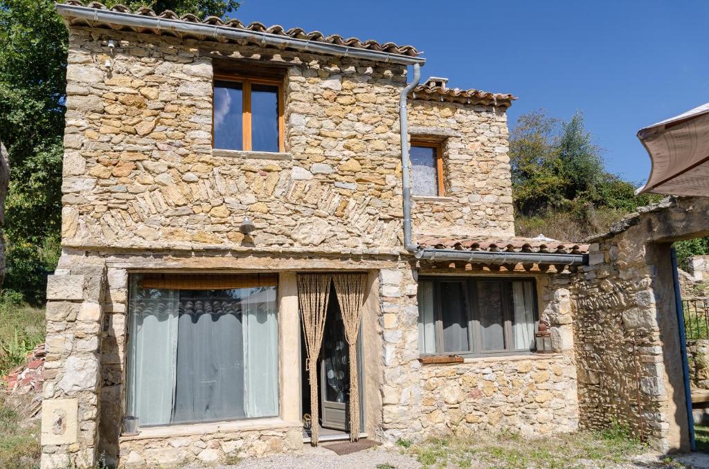 an old stone house with three windows on it at L'Oustaou des Monges in Mollans-sur-Ouvèze