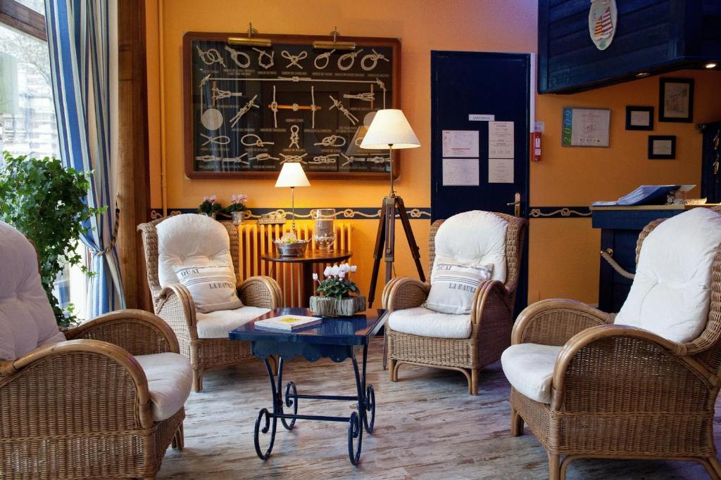 una camera con tavolo e sedie in vimini di Hotel Vent d'Ouest a Fécamp