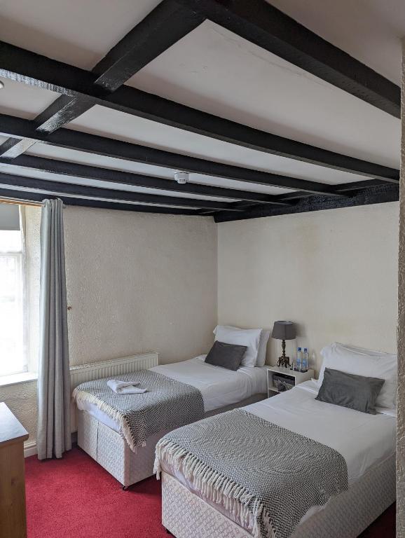 a bedroom with two beds and a ceiling with beams at George Inn st briavels in Lydney