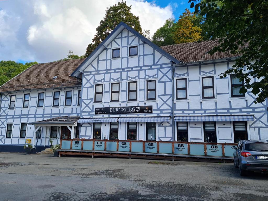 ein blau-weißes Gebäude mit einem Auto, das vorne parkt in der Unterkunft Gasthaus "Burgstieg" in Stiege