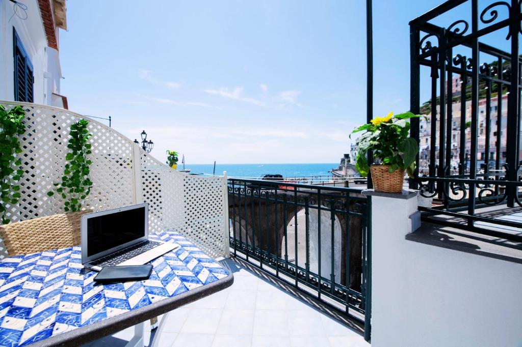 un ordinateur portable assis sur une table sur un balcon dans l'établissement Maison Escher, à Atrani