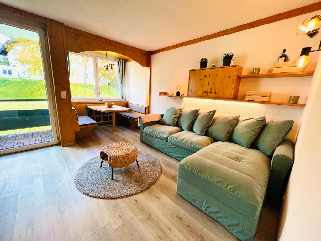 a living room with a green couch and a table at Wellness-Apartment Seefeld and Chill SPA im Zentrum mit Pool, Sauna und Netflix for free in Seefeld in Tirol