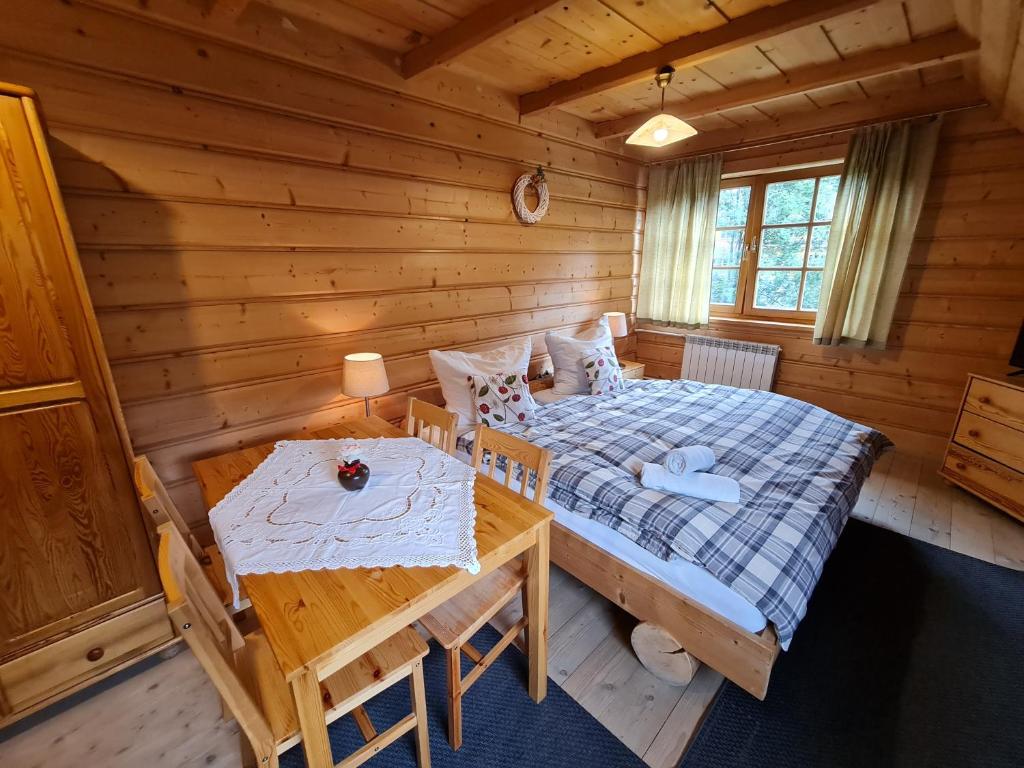 Dormitorio con cama y mesa en una cabaña de madera en GliczarowSki u Zbója, en Zakopane