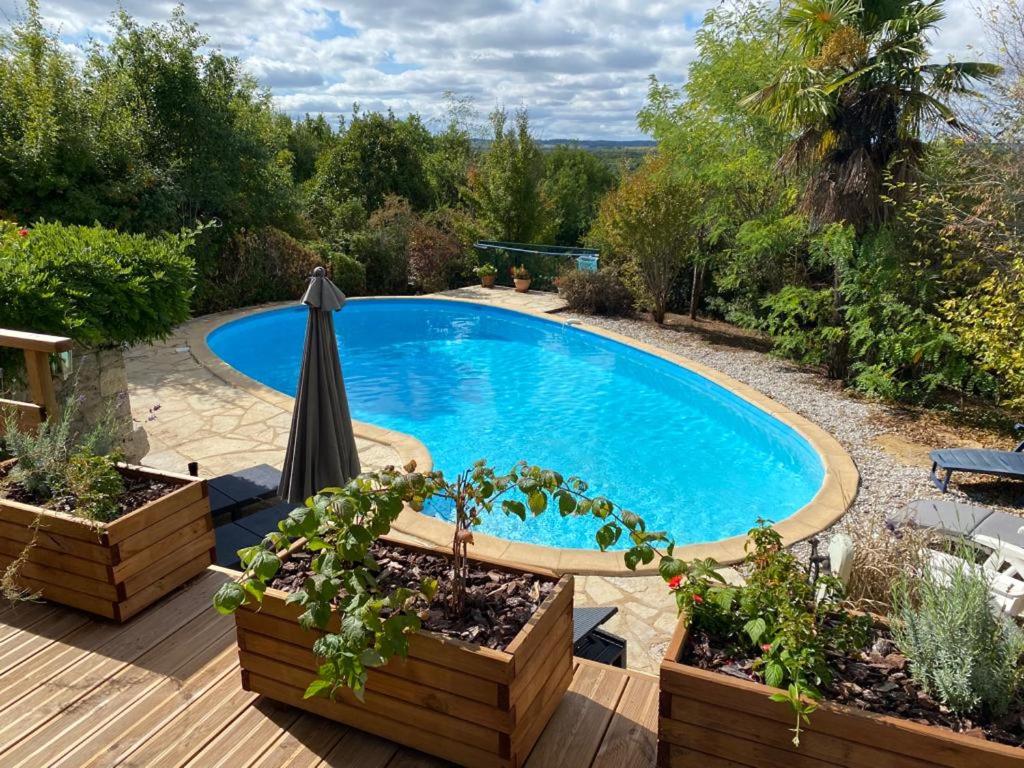 een zwembad in een tuin met een parasol bij Maison de 2 chambres avec piscine privee jardin amenage et wifi a Bruniquel in Bruniquel