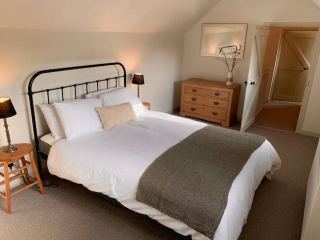 a bedroom with a large white bed and a wooden dresser at The Studio in Ashton Keynes