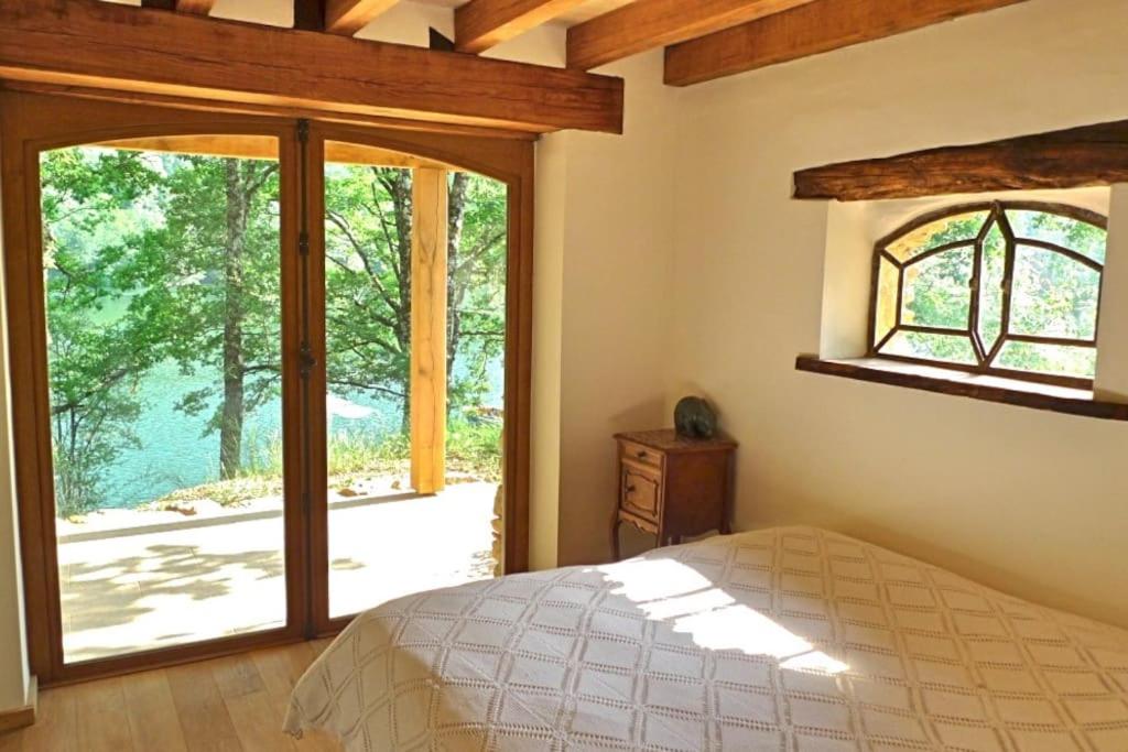1 dormitorio con cama y ventana grande en Lake House I // Alauzet Ecolodge + Nature spa en Castelnau-de-Mandailles