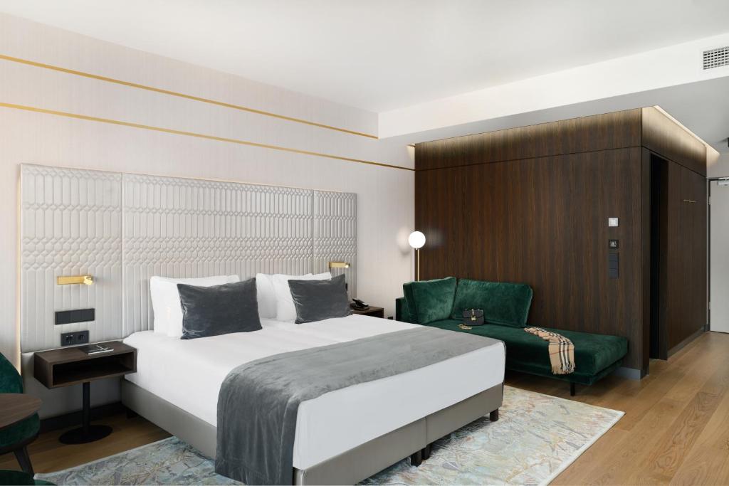 a bedroom with a large bed and a green chair at Emerald Hotel by Continental Group in Budapest
