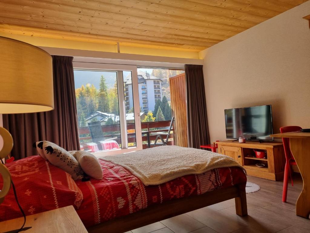 ein Schlafzimmer mit einem Bett und einem großen Fenster in der Unterkunft Magnifique studio rénové au coeur des 4 Vallées in Nendaz