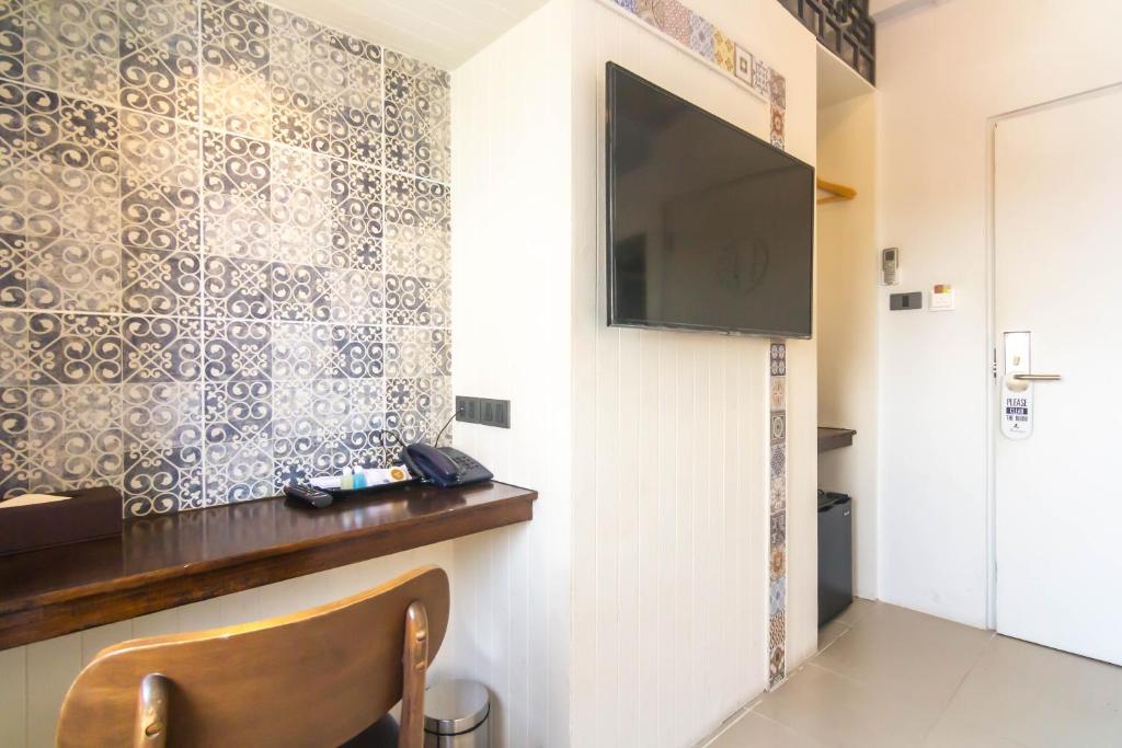 a small room with a television and a chair at Montree Phuket Hotel in Phuket Town