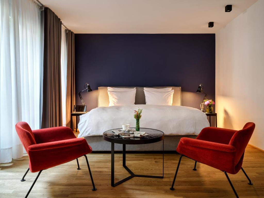 a bedroom with a bed and two red chairs at Boston Apartments HH in Hamburg