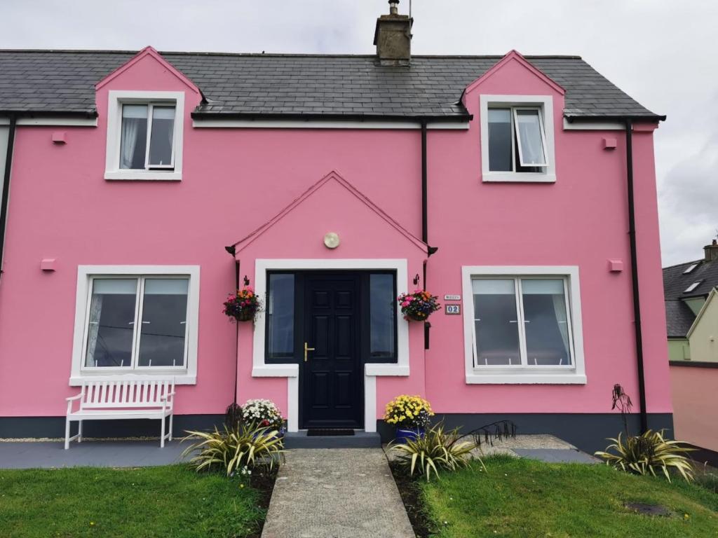 a pink house with a bench in front of it at Molly's Cottage Lahinch in Lahinch