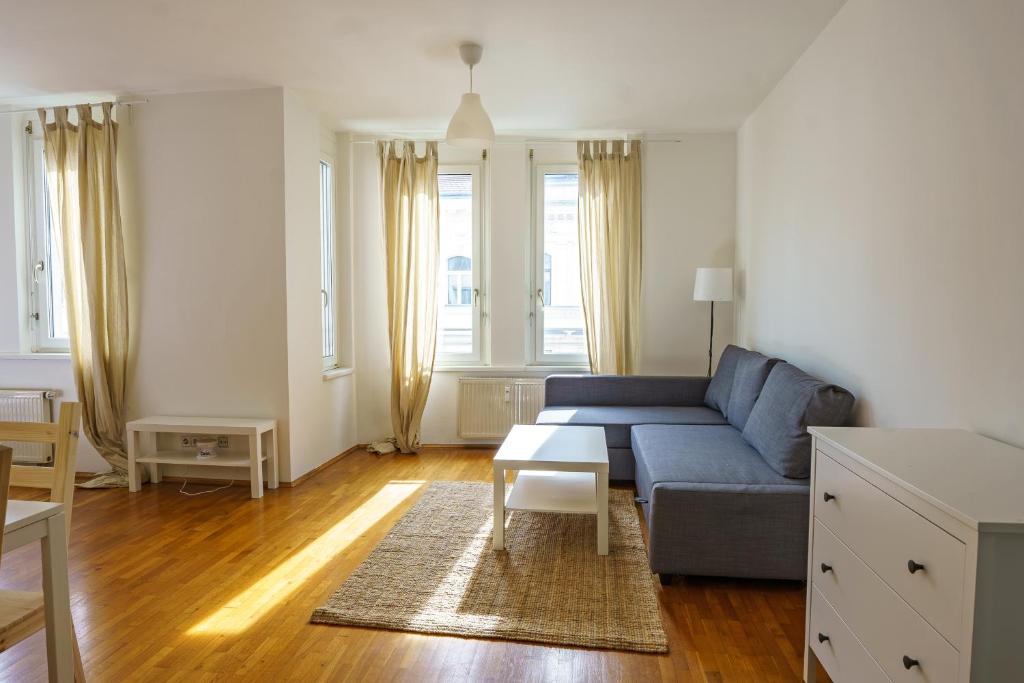 - un salon avec un canapé bleu et une table dans l'établissement Vienna Living Apartments - Lerchenfelder Straße, à Vienne