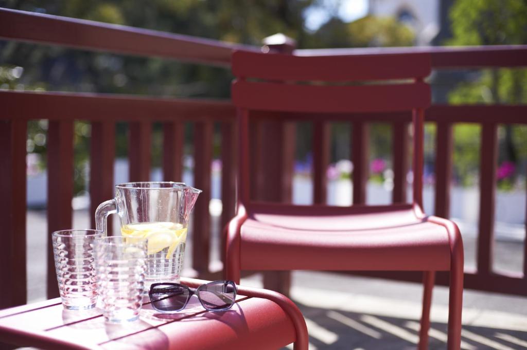 a table with glasses and a glass of lemonade on a chair at Hôtel Le Saint Christophe in La Baule