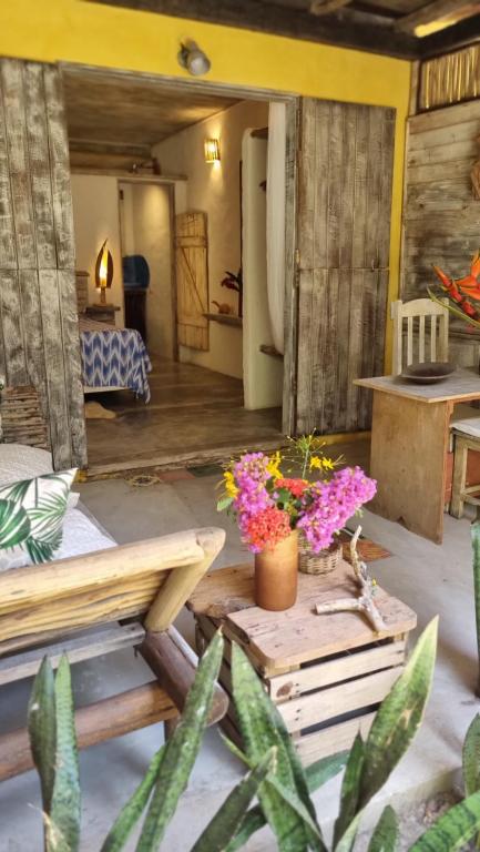 Una habitación con una mesa con flores. en Casa Namoa Pousada, en Isla de Boipeba