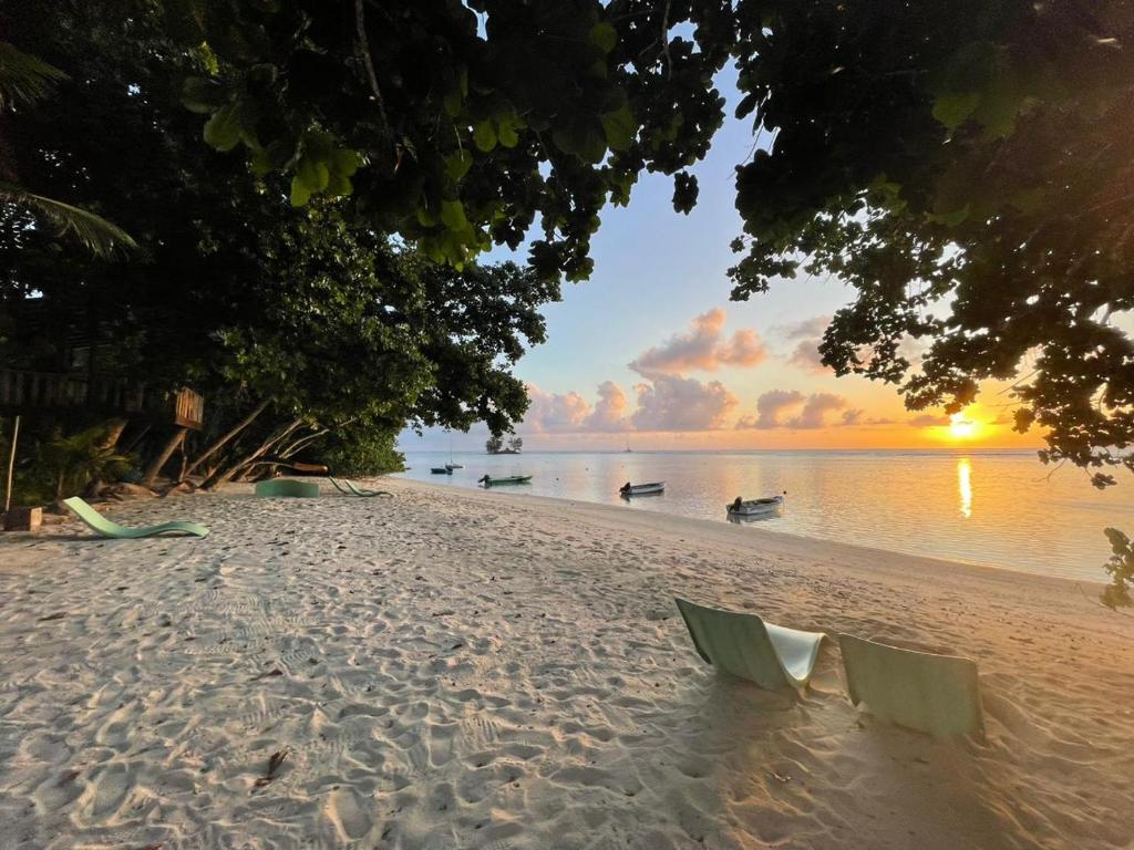 a beach at sunset with chairs on the sand at La Digue Luxury Beach & Spa in La Digue