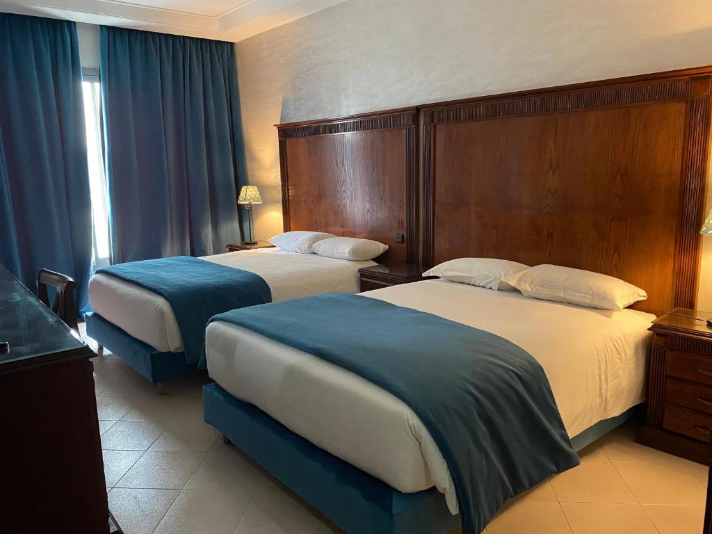 a hotel room with two beds with blue sheets at Hotel Azur in Casablanca