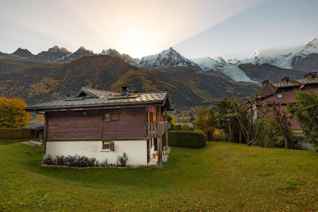 une maison dans un champ avec des montagnes en arrière-plan dans l'établissement Appartement les Bleuets, à Chamonix-Mont-Blanc